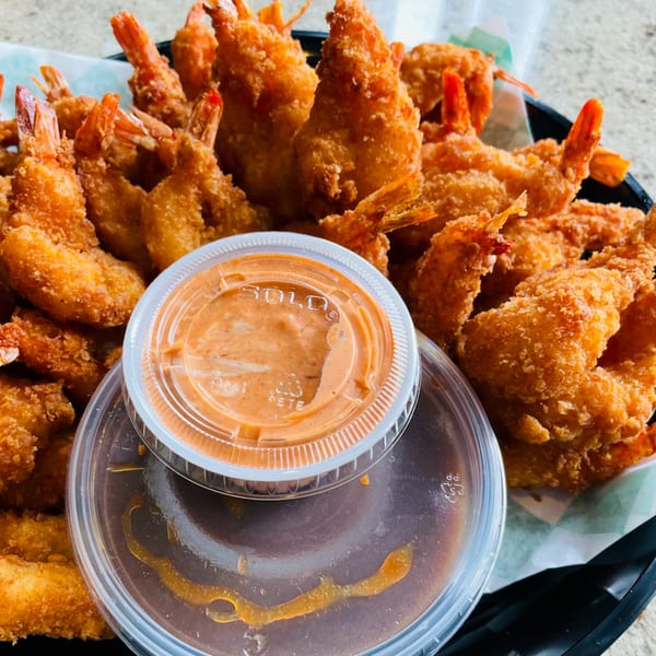 A basket of crispy fried shrimp with two containers of dipping sauce from Saigon Cafe Millburn.