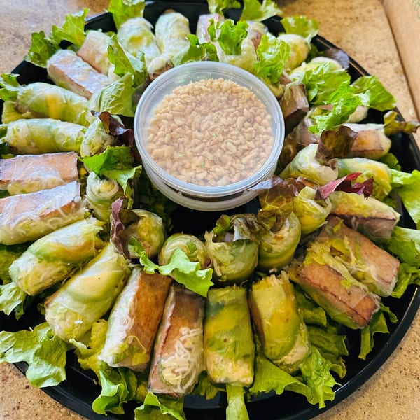 A platter of fresh Vietnamese spring rolls and summer rolls with a side of crushed peanuts.