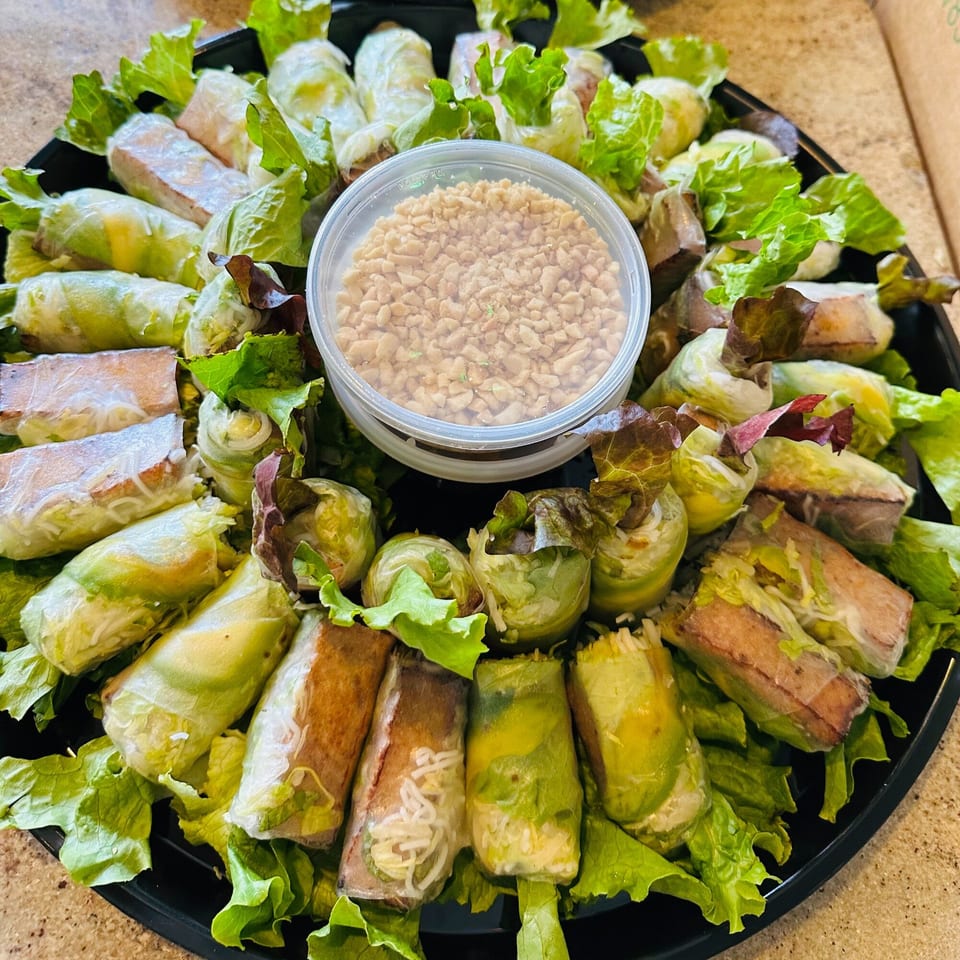 A platter of fresh Vietnamese spring rolls and summer rolls with a side of crushed peanuts.
