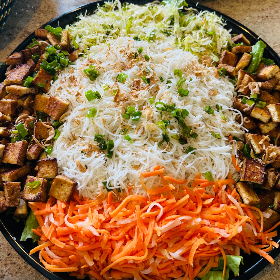 A large platter of Vietnamese vermicelli noodles, shredded cabbage, carrots, and crispy tofu.