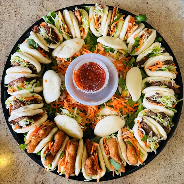 A large platter of Vietnamese bao buns with various fillings, including beef, shrimp, and tofu.