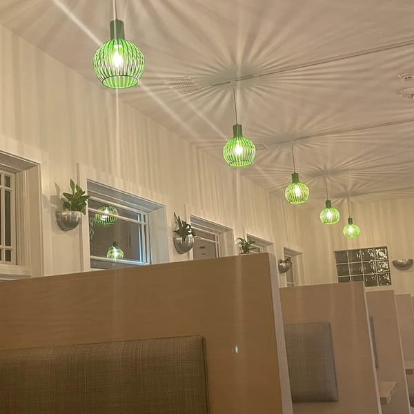 Interior of Saigon Cafe with green pendant lights casting starburst patterns on the ceiling, and booth seating.