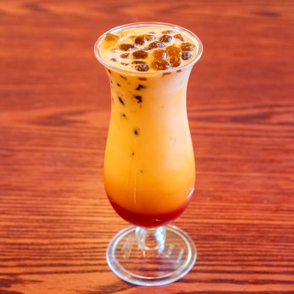 Thai iced tea with boba pearls in a tall glass on a wooden table.