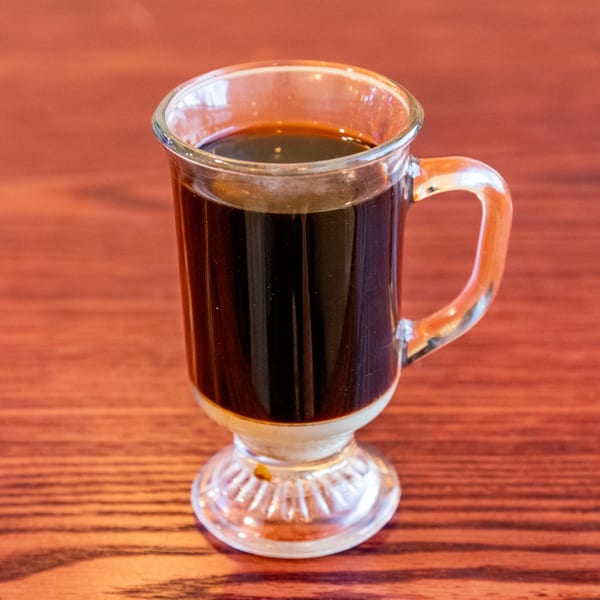 Vietnamese iced coffee in a clear glass mug with condensed milk at the bottom.