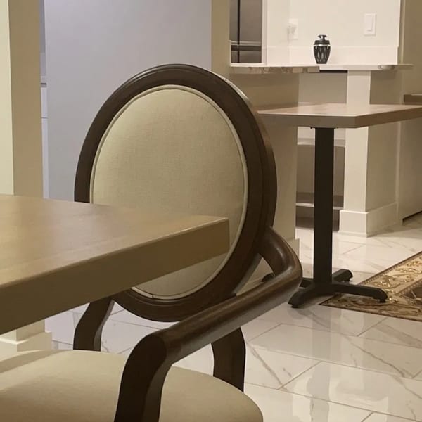 Elegant dining chair and table in a brightly lit restaurant interior with white tiled floors.